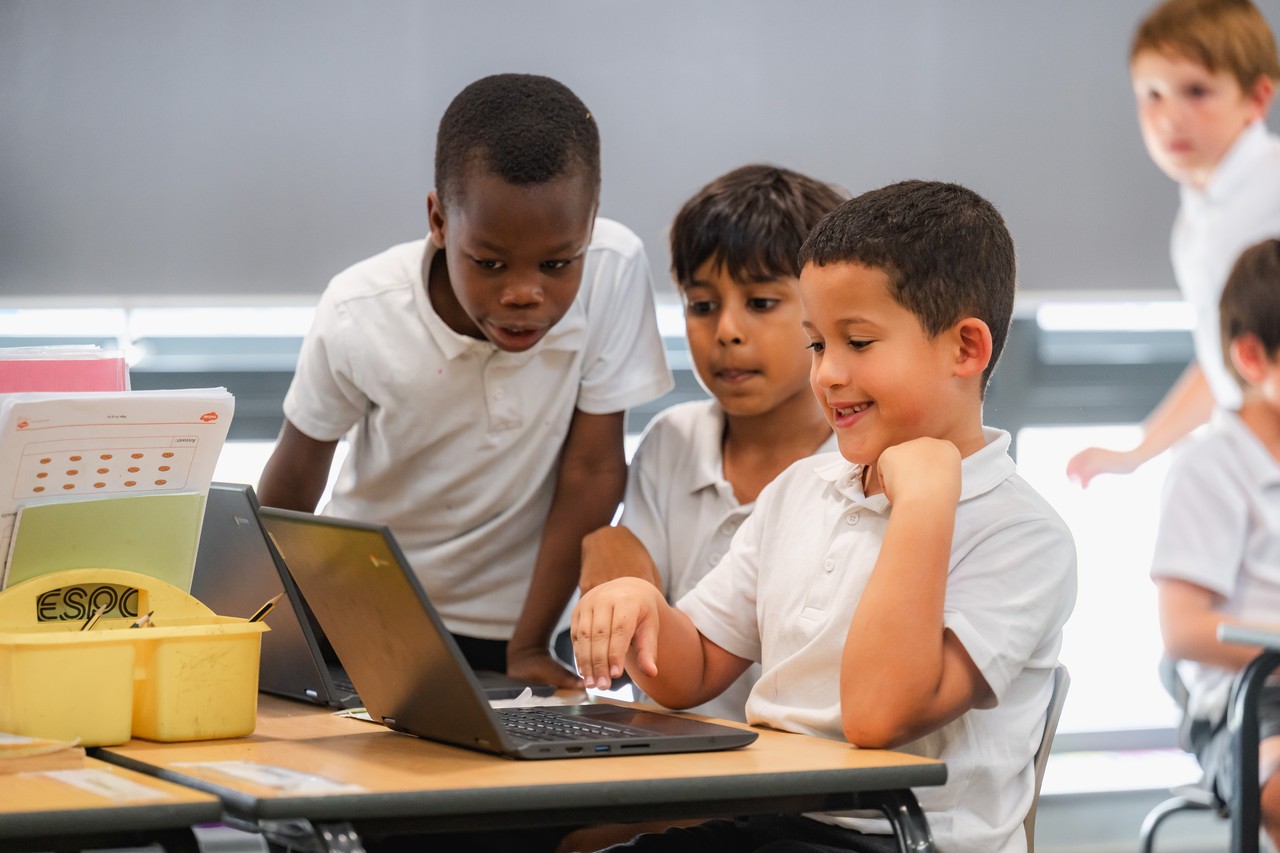 A group of children engaged in an activity on a laptop A group of children engaged in an activity on a laptop