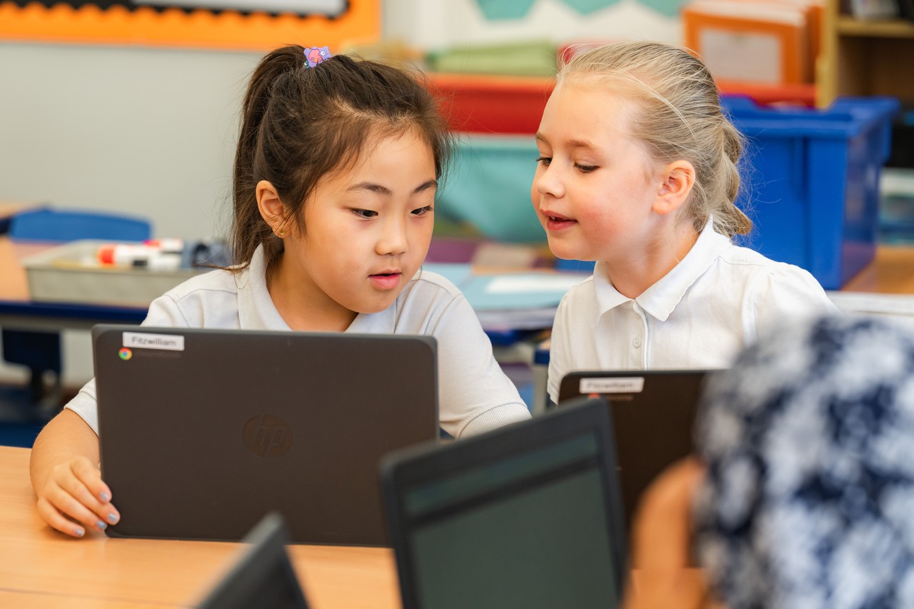 Two girls looking at laptops Two children looking at laptops