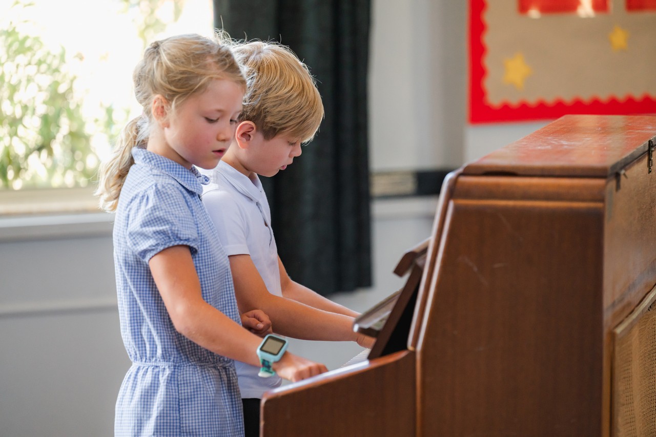 Two children playing the same piano