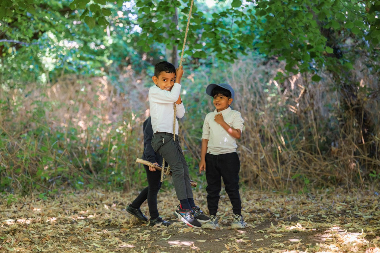 A child on a rope swing while another child looks on