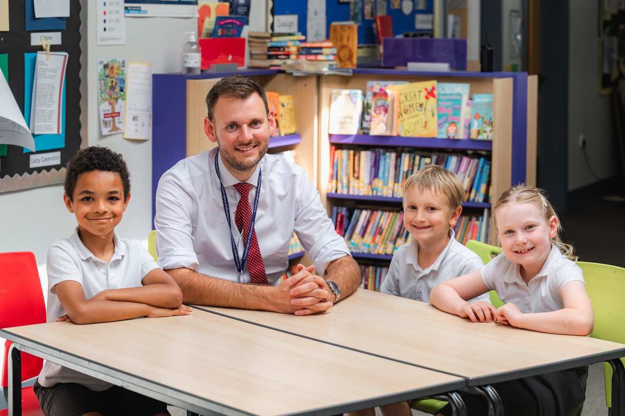 The headteacher seated at a table with children on either side
